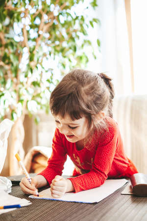 Smiling cute little girl 4-5 years old coloring pages and painting. Preschooler learning to draw.の写真素材