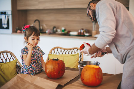 Little girl and her father scooping out pumpkins together for Halloween. Family spending time together.の写真素材