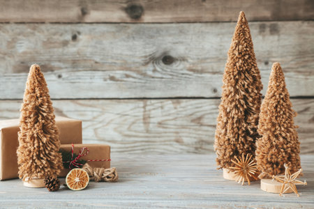Small fiber Christmas trees with gift boxes on a wooden background, zero waste concept