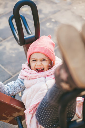Cute laughing little girl likes to swing at the playgroundの写真素材