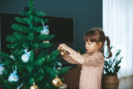 Cute little girl hanging ornaments and balls on Christmas tree. Kid decorating Christmas tree.の写真素材