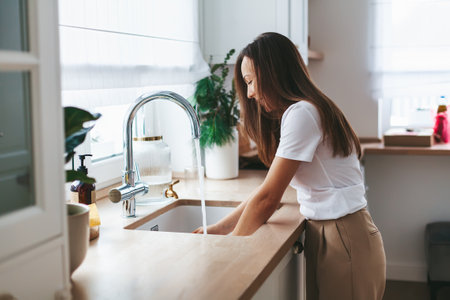 Young woman washing the dishes in the white kitchen at homeの写真素材