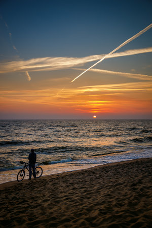 A cyclist woman enjoying the sea's breathtaking sunsetの写真素材