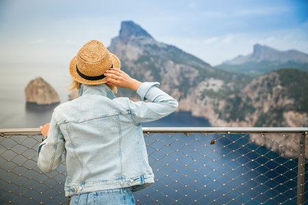 Woman in straw hat looking at the Cap de Formentor in Mallorca, Spainの写真素材