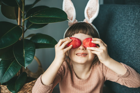 Portrait of a cute little girl with rabbit ears playing with Easter dyed or colored eggs. Easter conceptの写真素材