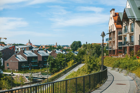A scenic view of Vilnius residential districts Paupys and Uzupis, showcasing a blend of modern and traditional architecture amidst lush greenery, under a clear blue skyの写真素材