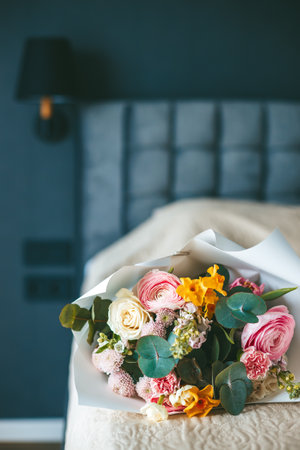A colorful bouquet of flowers on a neatly made bed, set against the backdrop of a bedroom, creating a scene of elegance and tranquilityの写真素材