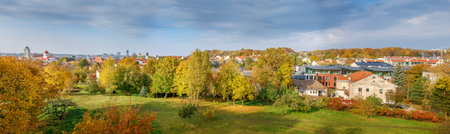 An autumn panorama of Vilnius, Lithuania, highlighting yellow and orange trees, with a blend of...