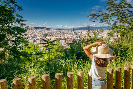 Barcelona's scenic skyline as seen from above, with a young girl wearing a straw hat, appreciating the vast array of buildings and landmarksの写真素材