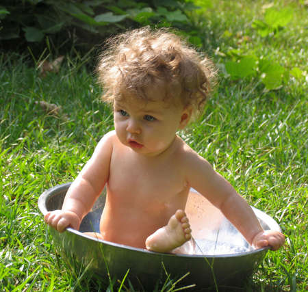 Baby taking a bath in a basin outdoorsの写真素材