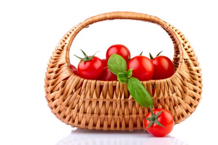 fresh tomatoes in basket isolated on white backgroundの写真素材