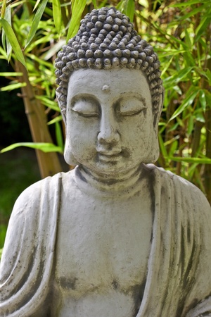 Buddha sculpture with bamboo leaves in backgroundの写真素材