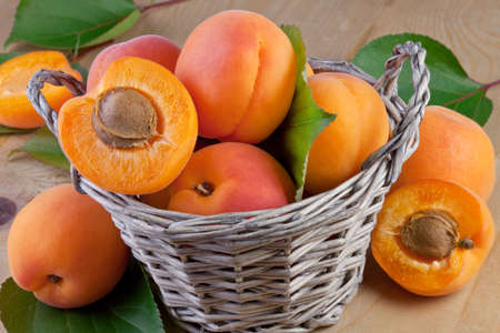 fresh apricot in wicker basket on wooden backgroundの写真素材