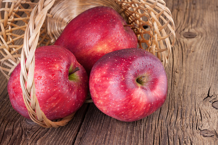 Red Apples in a Basket on Wooden Backgroundの写真素材