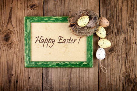Easter decoration with pastel color eggs in bird nest on old wood. Top view with text Happy Easter.の写真素材