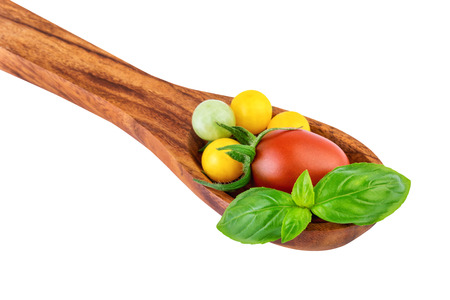 Tomatoes on wooden spoon with basil leaf cooking conceptの写真素材