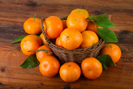 mandarin orange fruits in basket on old wooden tableの写真素材