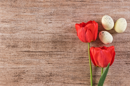 Holiday background with red tulips and Easter Eggs on light brown background. Text space, top viewの写真素材