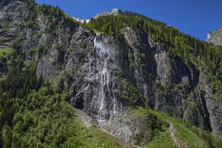 Mountain river stream, waterfall in the mountains, mountain creek among pines. Cascade falls over granite rocksの写真素材