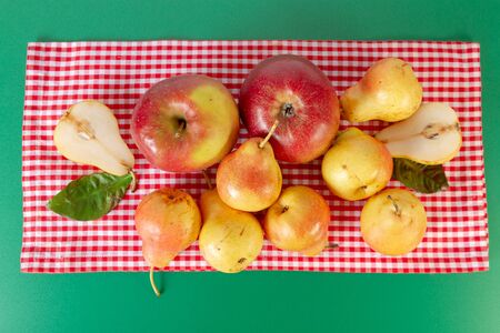 Pears and apples flat lay on green table with red checkered tablecloth. Autumn still life. Rustic design.の写真素材