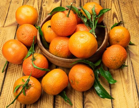 ripe organic mandarin fruits in wooden bowl over old wooden backgroundの写真素材