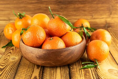 organic mandarin fruit in wooden bowl on wooden tableの写真素材