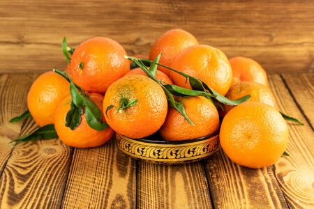 mandarin fruit in a oriental bowl on wooden tableの写真素材