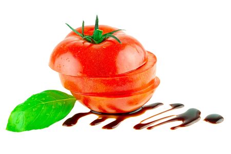 Tomato slisec with green basil leaf and balsamic vinegar isolatedの写真素材