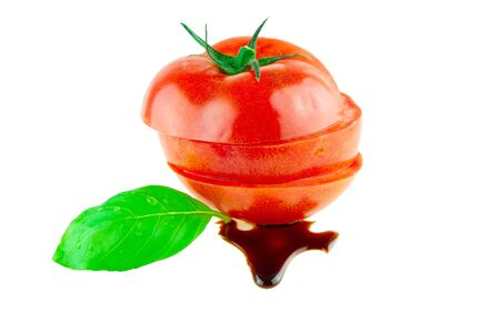 Tomato sliced in a pile with basil and balsamic vinegar isolated on whiteの写真素材