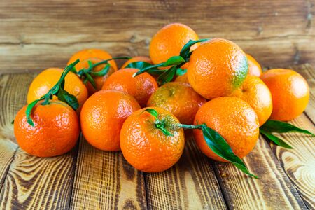 Organic mandarin orange fruits or tangerines scattered on old wooden tableの写真素材