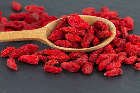 Goji berries close up dried red berry in wooden spoon on grey slate plateの写真素材