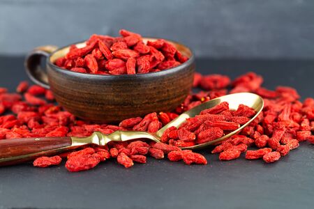 Goji berries in a cup and vintage spoon on gray slateの写真素材