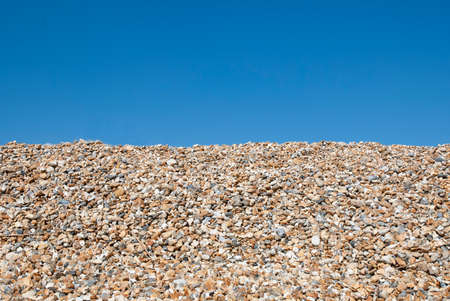 Pebbles on the beach on a sunny day with a blue sky in the background. Space for text.の写真素材