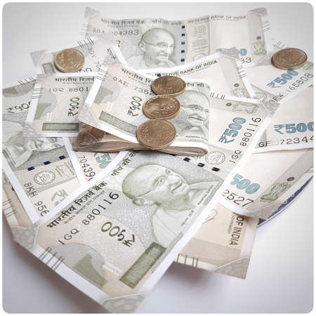 Indian new 500 rupees currency notes spread randomly with 5 rupee coins in white paperの写真素材