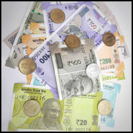 Indian new rupees currency notes spread randomly with 5 rupee coins in white paperの写真素材