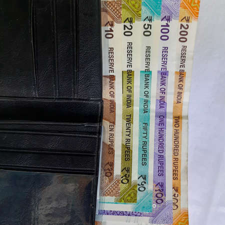 Indian new rupees currency notes arranged orderly number upwards manner with all rupee coins in white paper in walletの写真素材