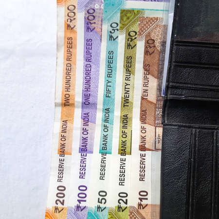 Indian new rupees currency notes arranged orderly number upwards manner with all rupee coins in white paper in walletの写真素材