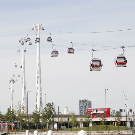 London , UK - May 26, 2013:  Gondolas of the Emirates Air Line cable car, opened June 2012, run by TFL, links the Greenwich Peninsula with Royal Dock, 1km, across the River Thames and the red double decker bus present.   
のeditorial素材
