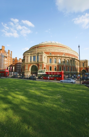 London, UK - May 26, 2013 : Outside view of Royal Albert Hall with green grass field, people and cars present on the street and a sightseeing bus passing by, Royal Albert Hall is a concert hall, most famous for summer Proms concerts since 1941, Completed のeditorial素材