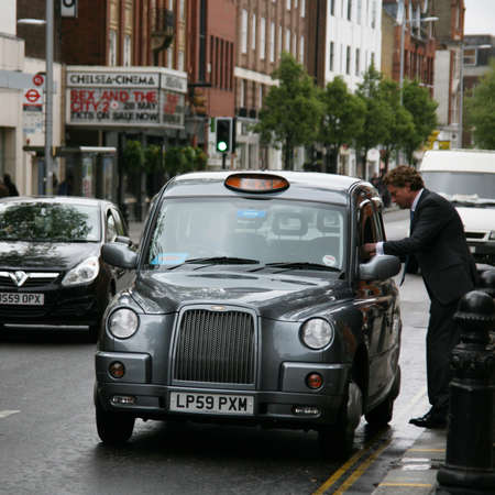 LONDON, UK - MAY 8, 2010: Taxi in the street on May 8, 2010 in London, UK. One passenger talk to driver before boarding. Cabs are the most iconic symbol of London as well as London's Red Double Decker Bus.のeditorial素材