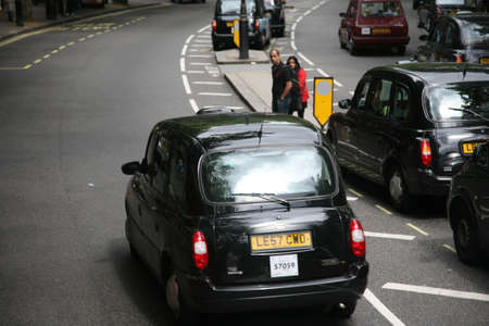 London, UK - August 12, 2010: Taxi in the street of London. padestrians looking for the chances to cross the road. Cabs are the most iconic symbol of London as well as London's Red Double Decker Bus.のeditorial素材