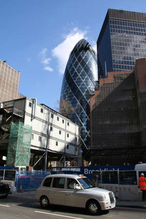 LONDON, UK - APRIL 8, 2010: Taxi in the street and 30 St Mary Axe in the distance on April 8, 2010 in London, UK. Cabs are the most iconic symbol of London as well as London's Red Double Decker Bus.のeditorial素材