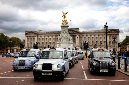 London, UK - October 27, 2012: London Taxi, also called hackney carriage, black cab. Buckingham Palace in the back ground. Traditionally Taxi cabs are all black in London but now produced in various colors.のeditorial素材