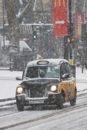 London, UK - Feb 28, 2018: Snow Covered London Taxi, also called hackney carriage, black cab. Traditionally Taxi cabs are all black in London but now produced in various colors.のeditorial素材