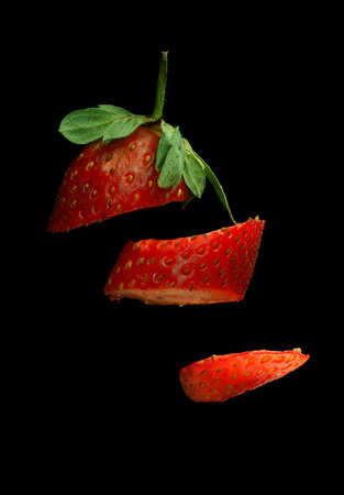 Floating sliced strawberry on isolated solid black backgroundの写真素材