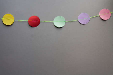 garland of yellow, red, mint, violet and pink paper circles on a gray background. party bannerの写真素材