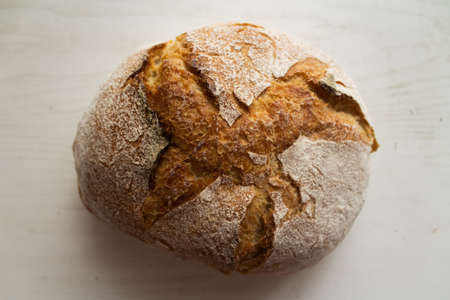 Fresh baked wheat bread on a white wooden background. Flat lay style