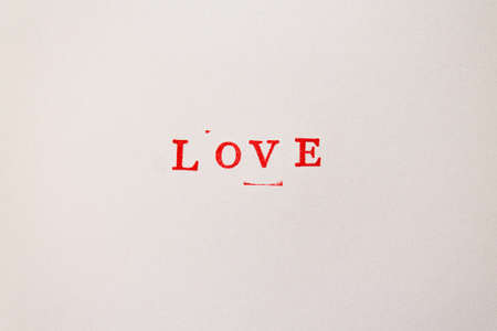 Love word printed in red ink on a white background in stamps tecknique. close up.の写真素材