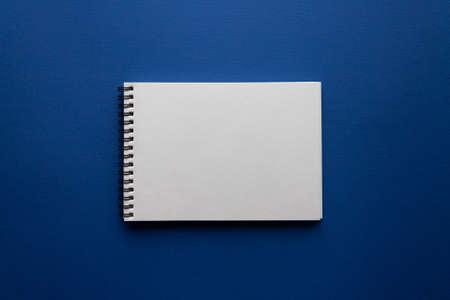 Open blank spiral notebook on trendy classic blue background. Minimalism. Flat lay style. Top view. Place for textの写真素材