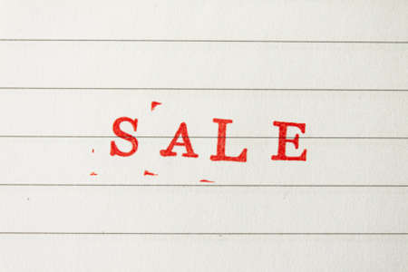 The red word sale stamped on a white lined paper. Price reduction and promotion in trade and services concept photoの写真素材